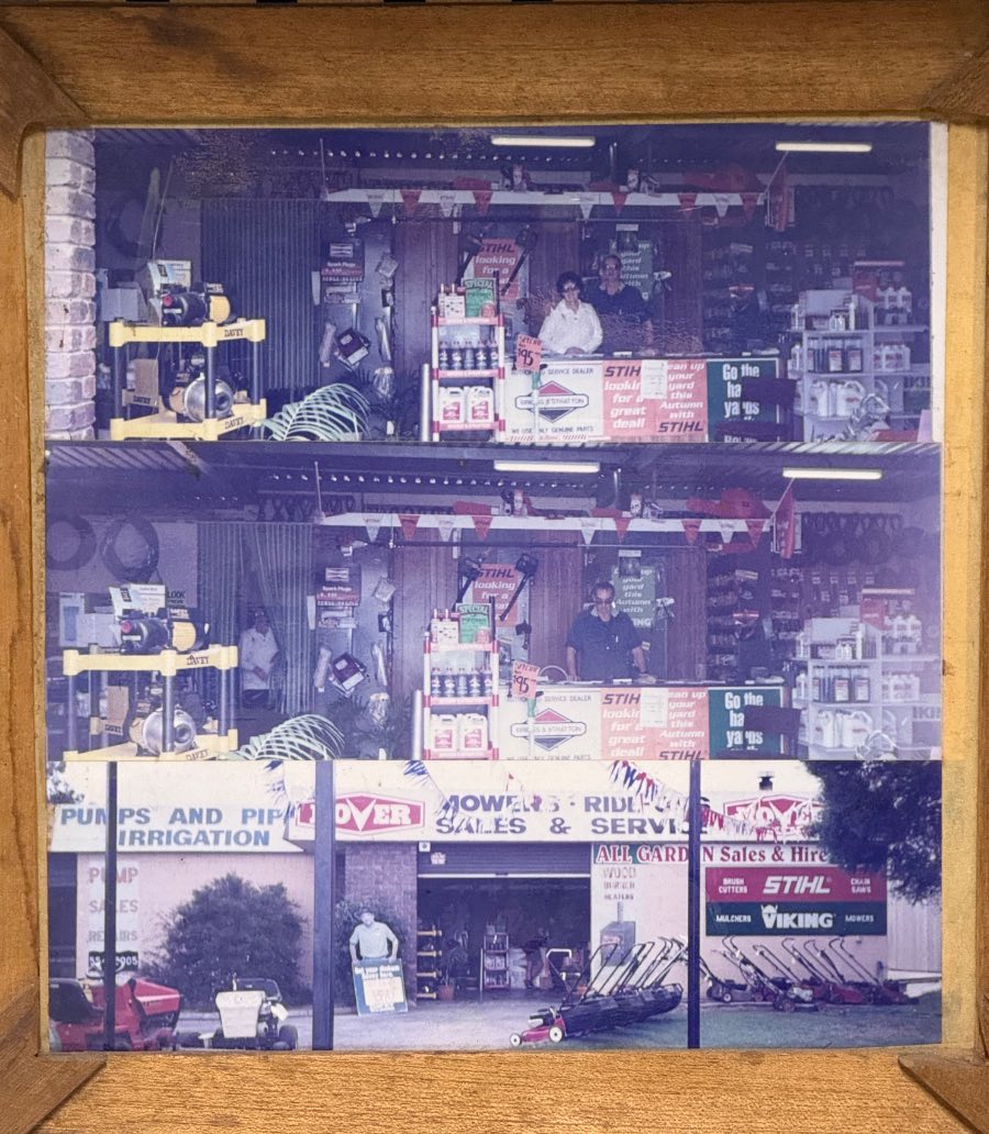 A framed set of old photographs hanging in the shop, showing the original Jimboomba store: staff behind the counter inside, and the shopfront with signage reading pumps and pipe, irrigation, and mowers, ride-on sales and service.